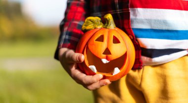 Cadılar Bayramı 'nda balkabağı lambasını tutan bir çocuk. Sonbahar tatili geçmişi kavramı.