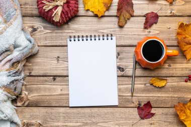 Masaüstü planlayıcısı. Üst görünüm dizüstü bilgisayar, balkabağı stili kahve ve sonbahar temalı dekorasyon, ahşap arka planda düşmüş yapraklar. Düz yat, boşluğu kopyala