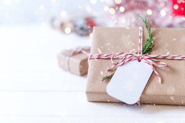 Noel hediyesi ve boş etiket. Işıl ışıl kar bokeh, kozalaklı dal. Kış tatilleri beyaz arka planda geçiyor. Sıfır atık, plastik yok