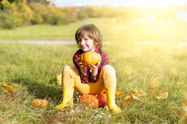 Tatlı çocuk Cadılar Bayramı 'nda sonbahar parkında balkabağıyla oynuyor. Çocuklar şeker mi şaka mı? Sonbaharda eğlence. Giyinik çocuk..