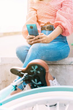 Bisikletli genç bir kadın cep telefonuyla sohbet ediyor.