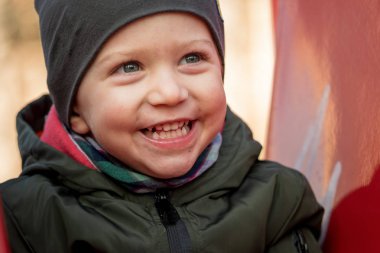 Yüksek sesle bir çocuk slayt üzerinde oturan gülüyor bir kap ile mutlu küçük çocuk yakın çekim.