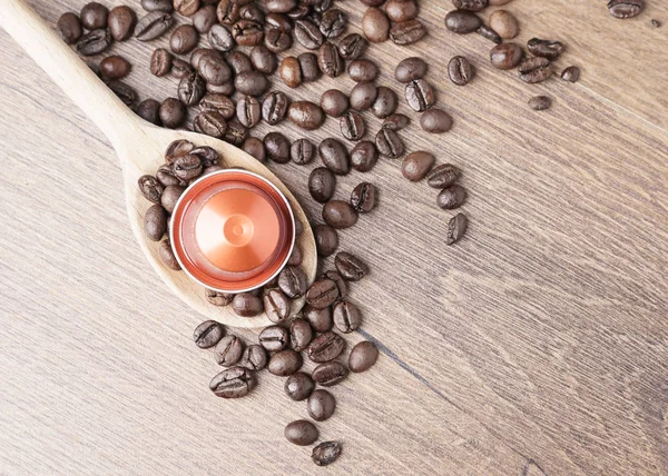 Coffee capsule on wooden spoon and  roasted coffee beans  on wooden background,top view,close up.