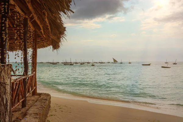 Güneş kirişler ile gün batımı içinde demirlemiş çeşitli balıkçı tekneleri ile harika bir plaj. Zanzibar Coast, Tanzanya.