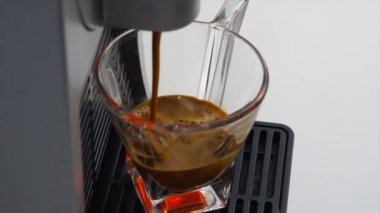 espresso kahve İtalyanca bir kapsül kahve makinesi ile yapılan en yüksek kalitede şeffaf cam kahve fincan içine düşer, kadar yakın zoom. kavram İtalya, sakin ol, biyo ve doğa.