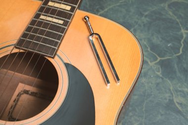 Akustik gitar gitar orada Yeşil mermer zemin üzerine olduğunu bir tuning çatal, müzik konsepti.