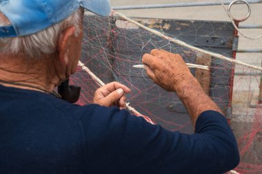 Kıdemli balıkçı bir balıkçı ağı tamir ediyor