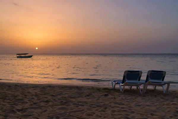 Gün batımında iki plaj sandalyesi ve tekne — Stok fotoğraf