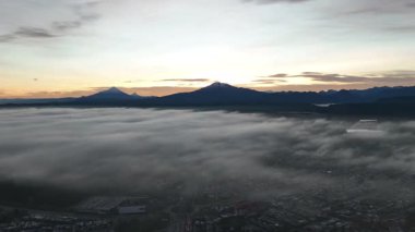 Güneşin doğuşunda volkanla birlikte Foggy Landscape 'in insansız hava aracı görüntüsü. Yüksek kalite 4k görüntü