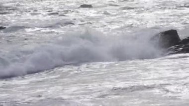 Okyanus Dalgaları Sunset 'te Rocky Shoreline' a çarpıyor. Yüksek kalite 4k görüntü