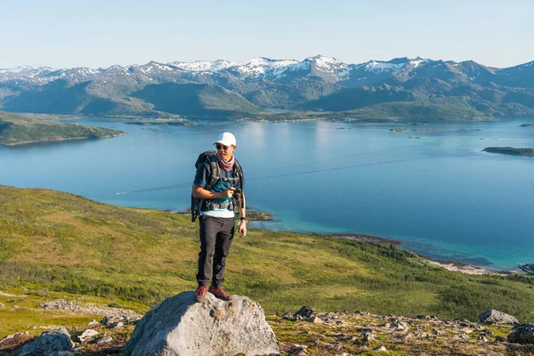 Yaz mevsiminde Norveç, İskandinavya, Avrupa 'daki Senja adasında kayalıklarda duran sırt çantalı genç Asyalı gezgin.
