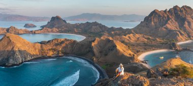 Asya 'nın Flores adasındaki Komodo milli parkında yaz mevsiminin ilk gündoğumunda Padar adasının tepesinde duran genç Asyalı gezgin. panoramik pankart bölümü