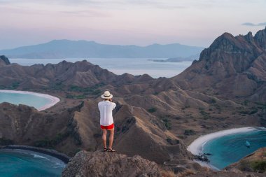 Genç Asyalı gezgin bir sabah Padar adasının tepesinde durup fotoğraf çekiyor yaz mevsiminde Flores adasındaki Komodo Ulusal Parkı, Endonezya, Asya