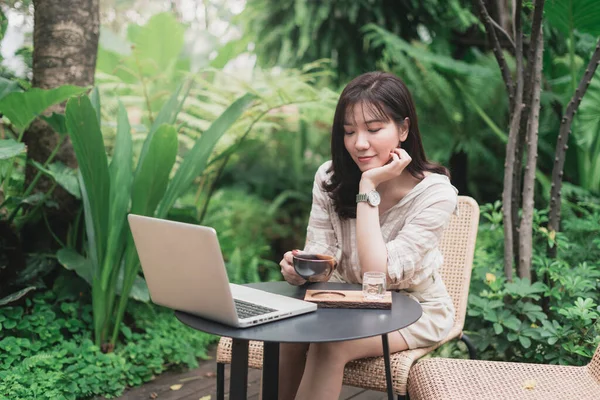 아시아 여성이 노트북 컴퓨터와 커피를 마시며 일하고 있습니다 얼굴을 여자가 스톡 사진