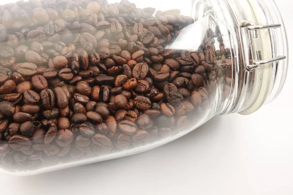 Raw coffee bean in a mason jar over white background