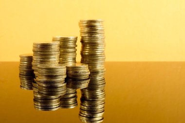 Kavramı ile bir sikke tasarruf sarı bir arka plan üzerinde yığılmış.