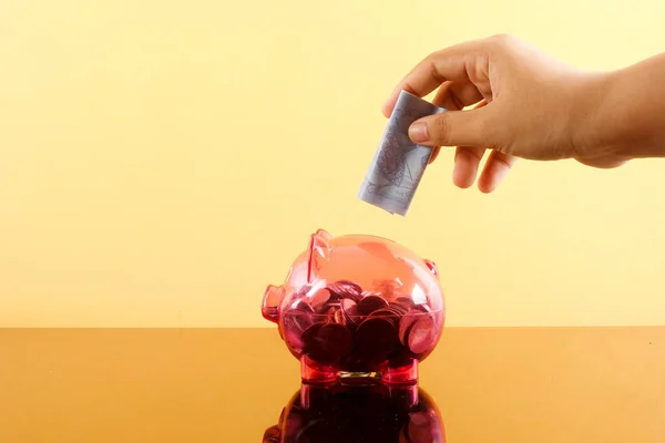 Saving Concept with red piggy bank and coins stacked on a yellow background.