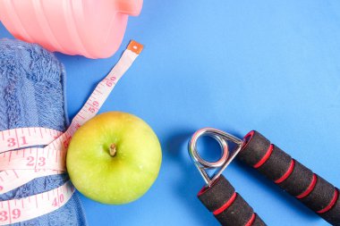 Fitness kavramı halter, el tutma, kule ve mavi bir arka plan üzerinde ölçüm bandı ile.