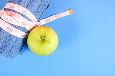 Fitness kavramı halter, el tutma, kule ve mavi bir arka plan üzerinde ölçüm bandı ile.