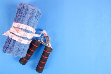 Fitness kavramı halter, el tutma, kule ve mavi bir arka plan üzerinde ölçüm bandı ile.