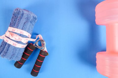 Fitness kavramı halter, el tutma, kule ve mavi bir arka plan üzerinde ölçüm bandı ile.