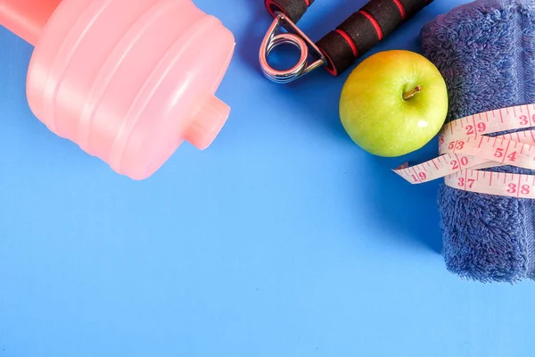 Fitness kavramı halter, el tutma, kule ve mavi bir arka plan üzerinde ölçüm bandı ile.