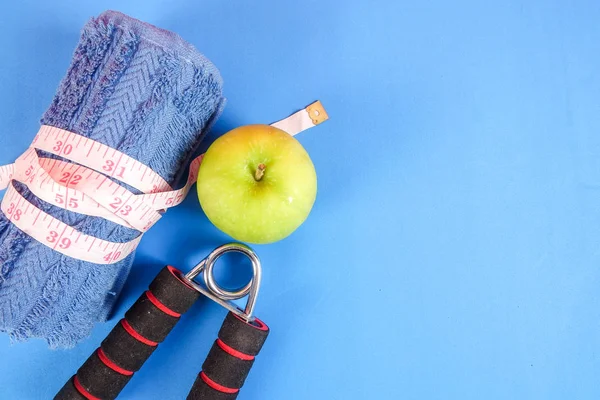 Fitness kavramı halter, el tutma, kule ve mavi bir arka plan üzerinde ölçüm bandı ile.