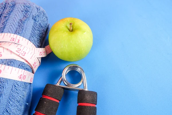 Fitness kavramı halter, el tutma, kule ve mavi bir arka plan üzerinde ölçüm bandı ile.