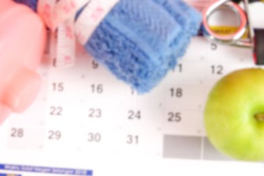 Bulanık görüntü: Fitness kavramı halter, el tutma, kule ve takvim arka plan üzerinde ölçüm bandı ile.