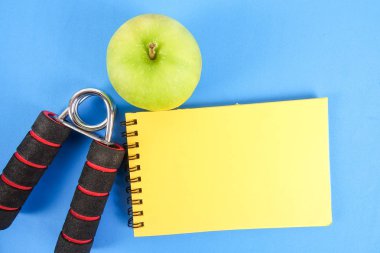 Fitness kavramı halter, el tutma, kule ve mavi bir arka plan üzerinde ölçüm bandı ile.