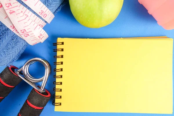 Fitness kavramı halter, el tutma, kule ve mavi bir arka plan üzerinde ölçüm bandı ile.