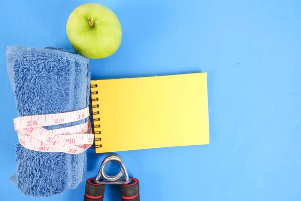 Fitness kavramı halter, el tutma, kule ve mavi bir arka plan üzerinde ölçüm bandı ile.