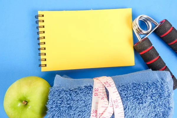 Fitness kavramı halter, el tutma, kule ve mavi bir arka plan üzerinde ölçüm bandı ile.