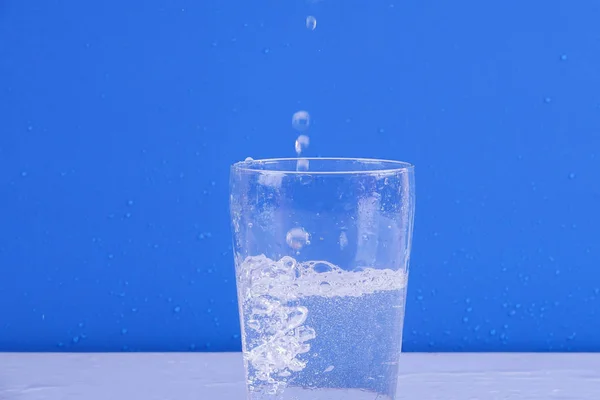 Wasser Spritzt Aus Glas Isoliert Auf Blauem Hintergrund — Stockfoto