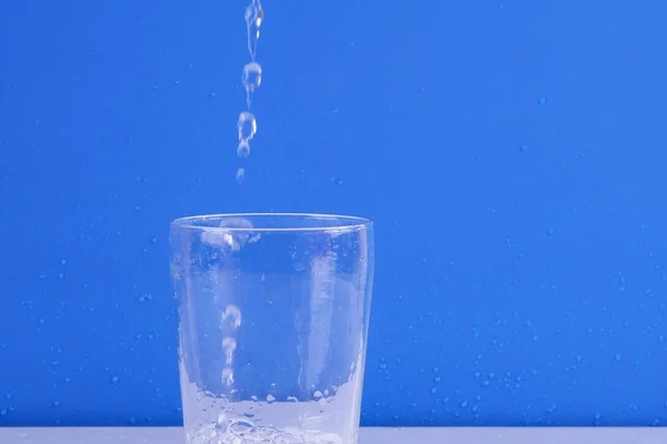 Salpicaduras Agua Vidrio Aislado Sobre Fondo Azul —  Fotos de Stock