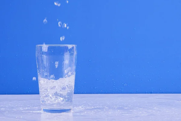 Вода Бризкає Скла Ізольовано Синьому Фоні — стокове фото