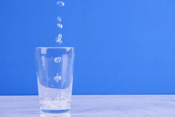 Water splashing from glass isolated on a blue background.