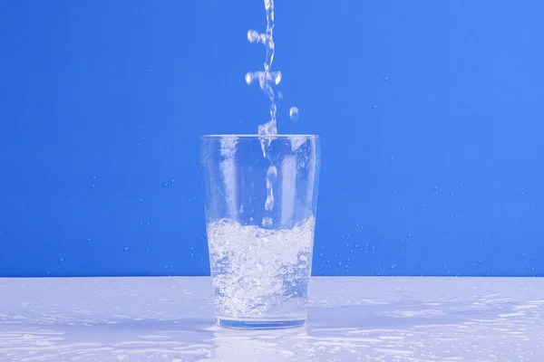 Wasser Spritzt Aus Glas Isoliert Auf Blauem Hintergrund — Stockfoto