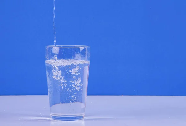 Wasser Spritzt Aus Glas Isoliert Auf Blauem Hintergrund — Stockfoto