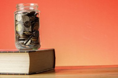 Eğitim Fonu kavramı ile paralar bir cam kavanoz ve eski kitap.