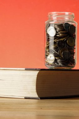 Eğitim Fonu kavramı ile paralar bir cam kavanoz ve eski kitap.