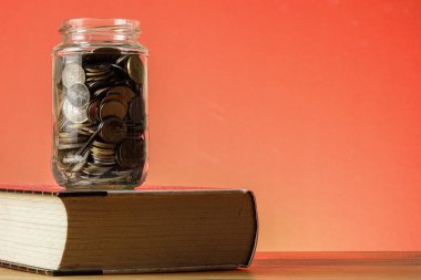 Eğitim Fonu kavramı ile paralar bir cam kavanoz ve eski kitap.