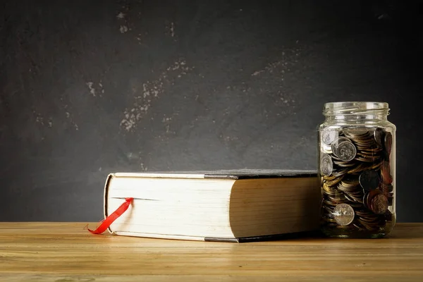 Eğitim Fonu kavramı ile paralar bir cam kavanoz ve eski kitap.