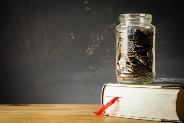 Eğitim Fonu kavramı ile paralar bir cam kavanoz ve eski kitap.