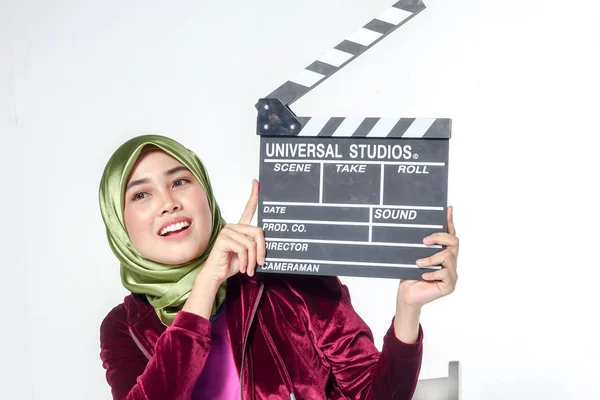 Young veiled pretty asian woman with clapperboard, Film production and movie making concept.