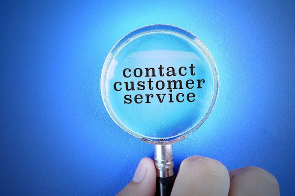 Hand holding magnify glass over a blue background with CONTACT CUSTOMER SERVICE words