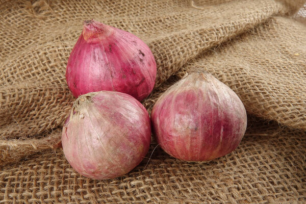 Onions on a brown rug background.
