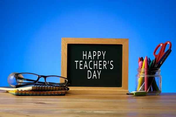 HAPPY TEACHER\'S DAY CONCEPT: School stationeries over a blue background.