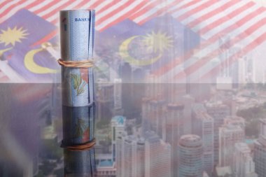 1 Malaysian Ringgit banknotes over a blur background of Malaysia flags and cityscape. clipart