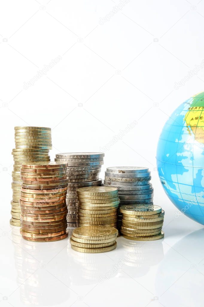 Global economy concept with sphere globe and stacked of coins over white.